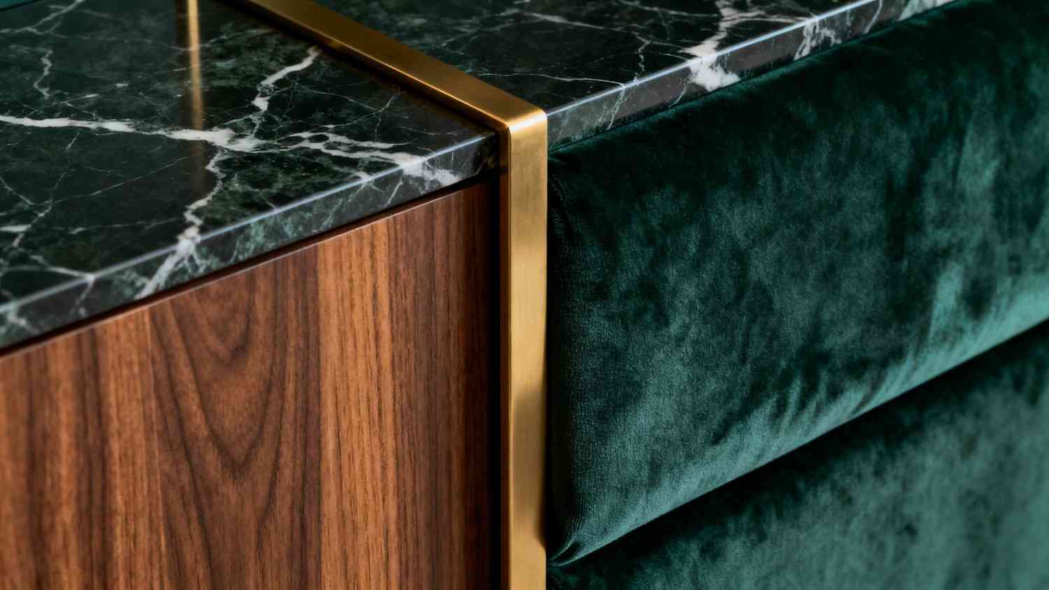 Detail of green marble, walnut and a brushed brass edge against velvet