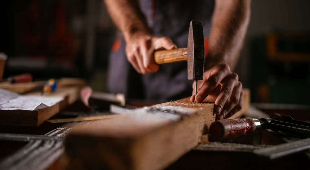 Hands working timber with a hammer and chisel